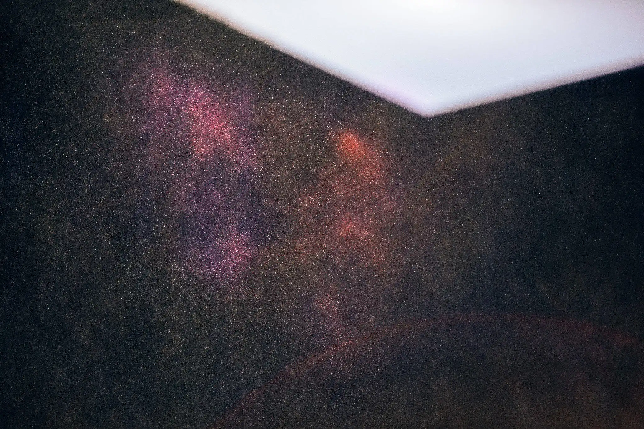 Abstraktes Foto von Partikeln, die vor einem Lichtpfeil schweben, der nach unten zeigt, um zu weiterem Scrollen zu animieren.